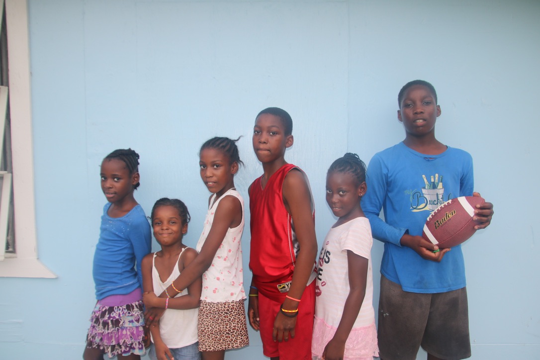 Children gathered against a blue wall in Abaco